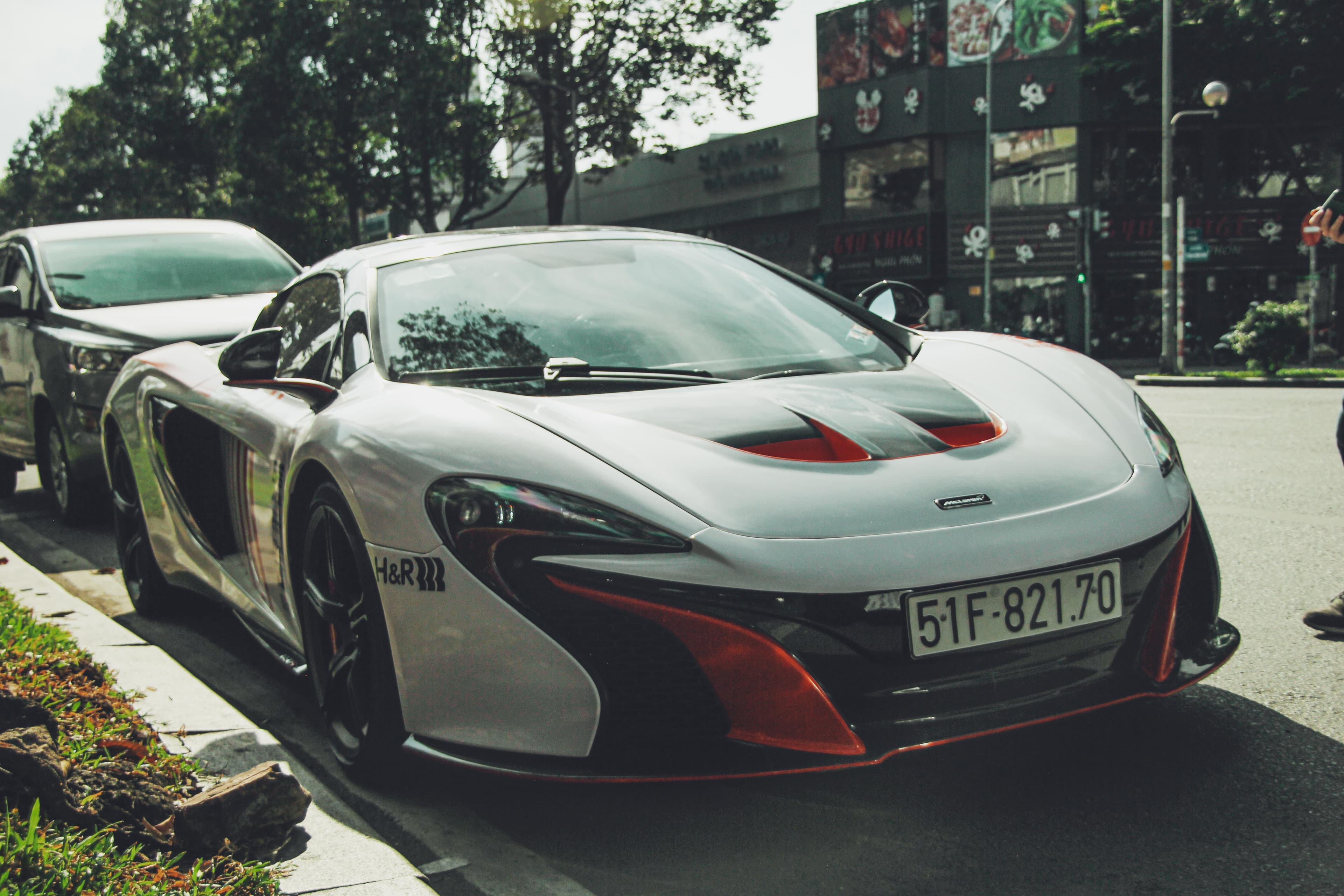 White McLaren 650S with red accents parked at a city kerb, seen from the front three-quarter